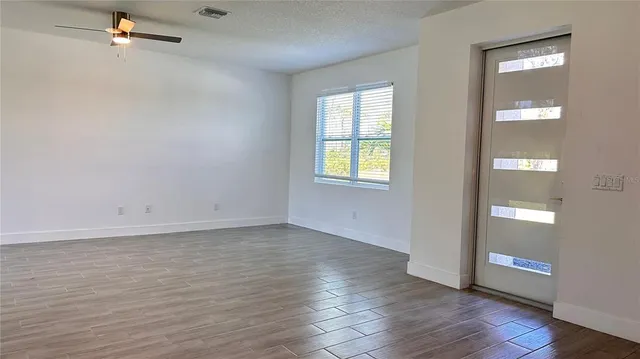 an empty room with wooden floor and windows