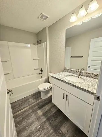 a backyard of a house with plants and large tree