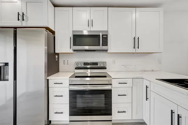 a kitchen with white cabinets and stainless steel appliances