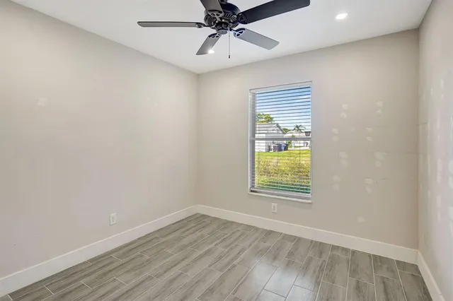 an empty room with a window and a ceiling fan