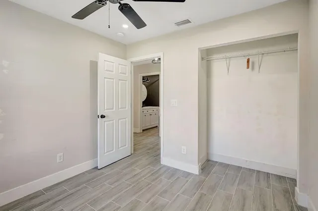 an empty room with wooden floor a ceiling fan and windows
