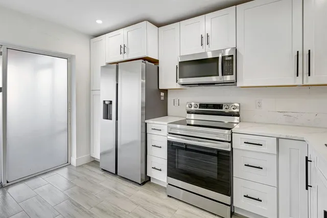 a kitchen with stainless steel appliances white cabinets white stove a microwave and a refrigerator