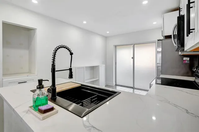 a living room with stainless steel appliances furniture a rug and a view of kitchen