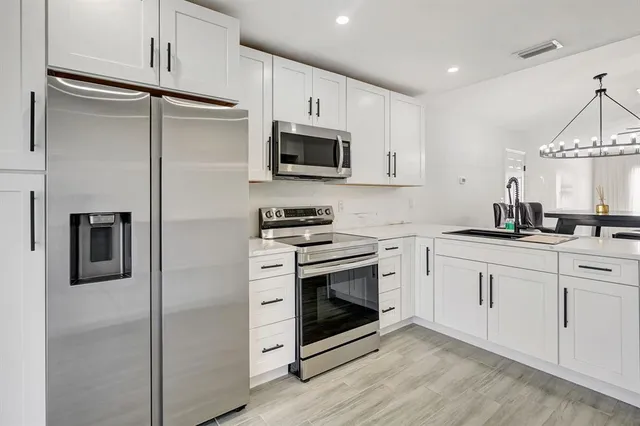 a kitchen with stainless steel appliances white cabinets a sink and a stove