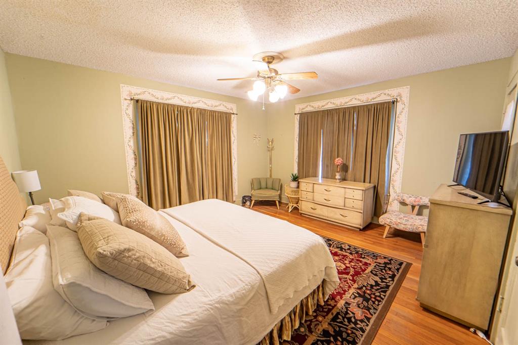 900 West Walker Street Breckenridge, TX 76424 - Photo 38 of 40 a bedroom with a bed and wooden floor