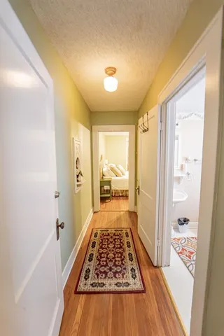 a view of a hallway to a livingroom with wooden floor and furniture