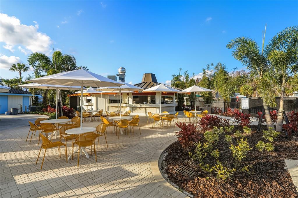 5475 Saddlebrook Way Wesley Chapel, FL 33543 - Photo 26 of 29 a patio with tables and chairs pool and a fire pit with wooden fence