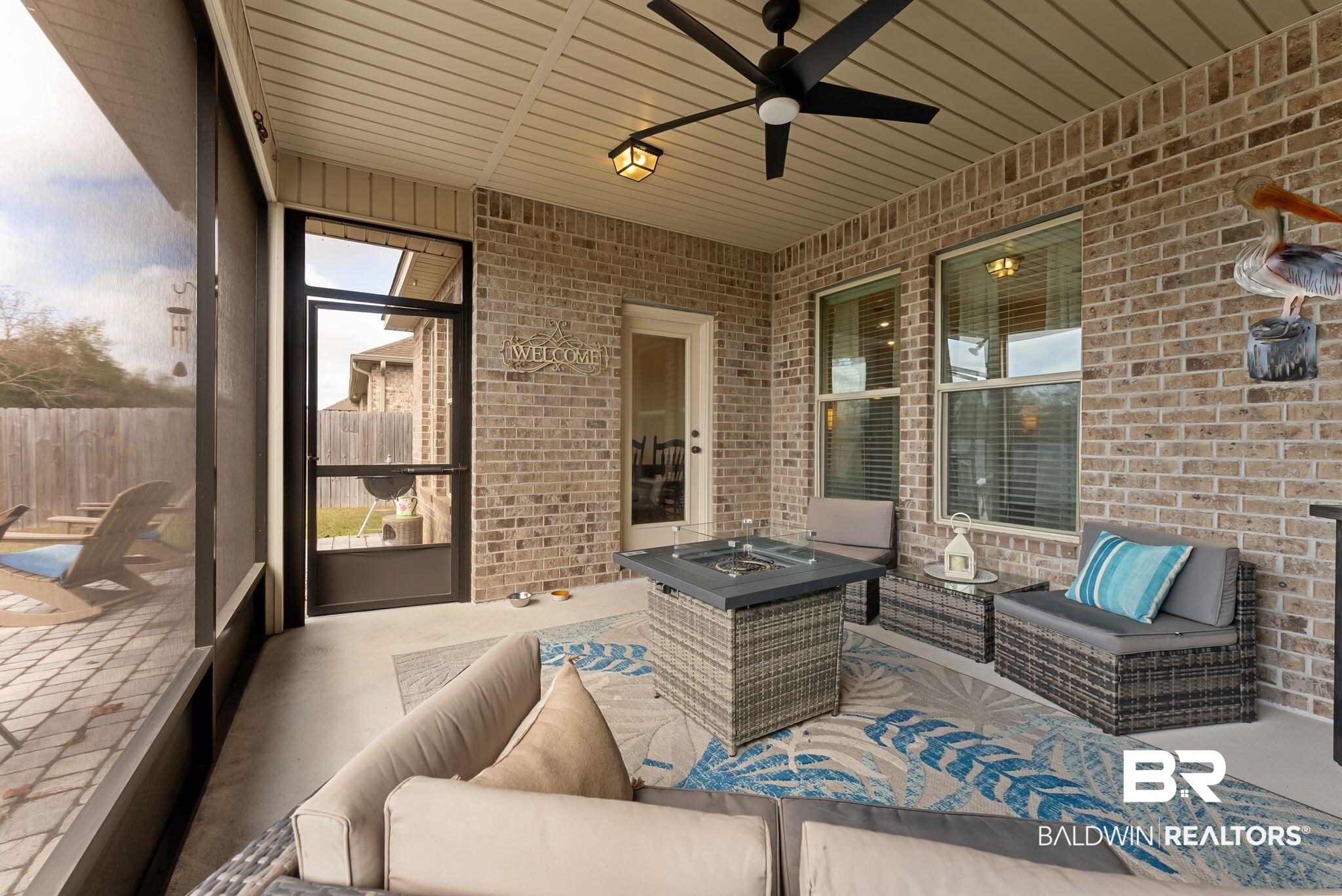 7015 Rocky Rd Loop Gulf Shores, AL 36542 - Photo 16 of 41 Sunroom featuring a patio area, an outdoor living space with a fire pit, ceiling fan, and plenty of natural light