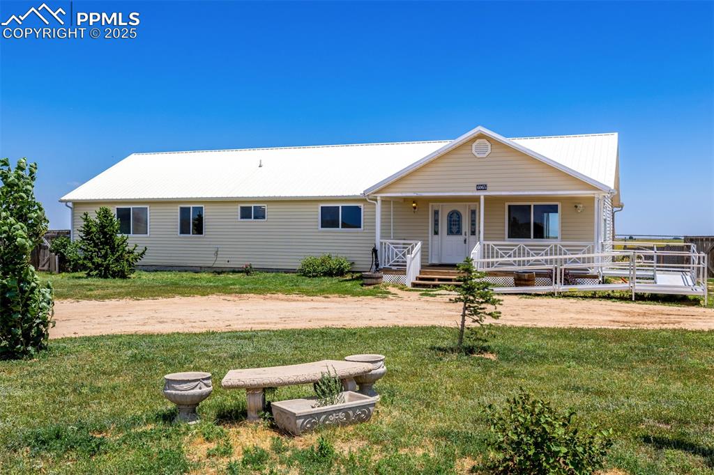 View of front of house featuring a front yard, a metal roof, and covered porch