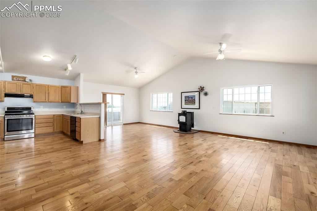 6065 Mulberry Road Calhan, CO 80808 - Photo 11 of 45 Kitchen with stainless steel range, open floor plan, a wood stove, under cabinet range hood, and ceiling fan