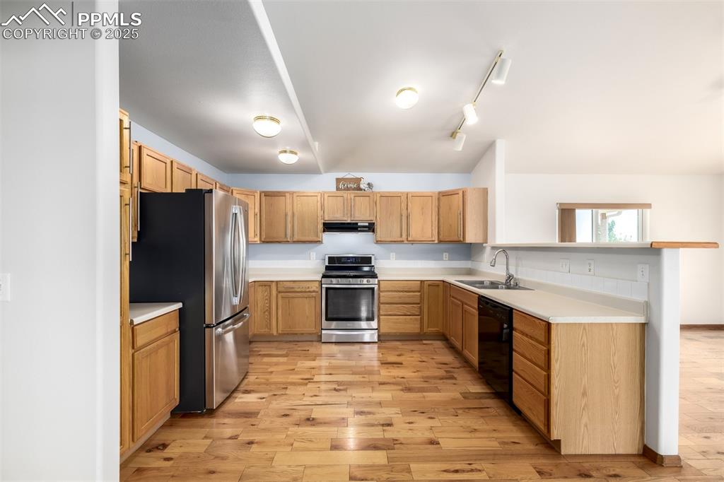6065 Mulberry Road Calhan, CO 80808 - Photo 12 of 45 Kitchen with appliances with stainless steel finishes, under cabinet range hood, light wood-style floors, and light countertops