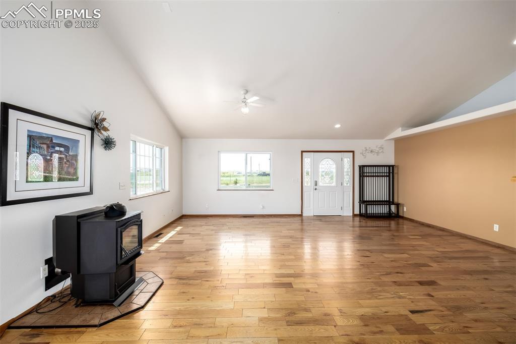 6065 Mulberry Road Calhan, CO 80808 - Photo 6 of 45 Unfurnished living room with ceiling fan, a wood stove, plenty of natural light, light wood-type flooring, and high vaulted ceiling