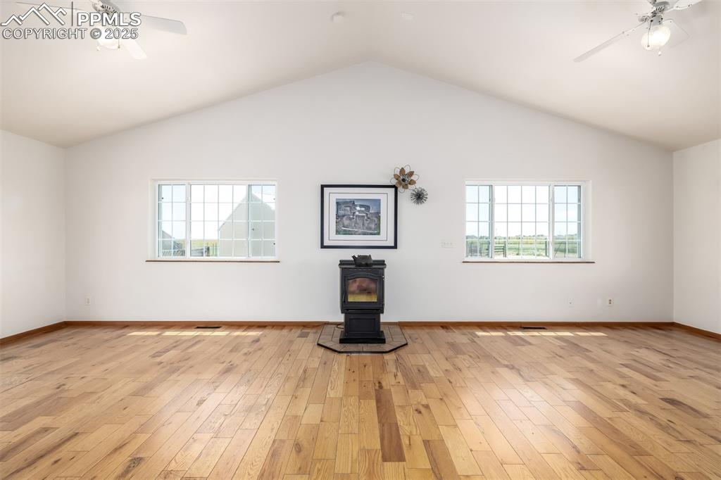 6065 Mulberry Road Calhan, CO 80808 - Photo 7 of 45 Unfurnished living room with a wood stove, plenty of natural light, light wood-style flooring, and vaulted ceiling