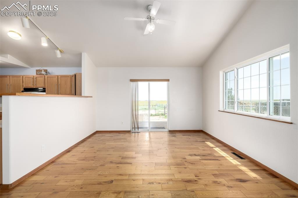 6065 Mulberry Road Calhan, CO 80808 - Photo 10 of 45 Unfurnished living room with plenty of natural light, light wood-style floors, vaulted ceiling, a ceiling fan, and track lighting