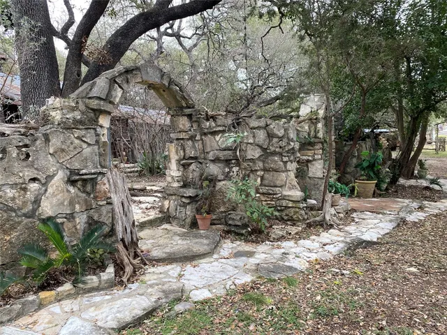 a view of a backyard with table and chairs potted plants and large tree