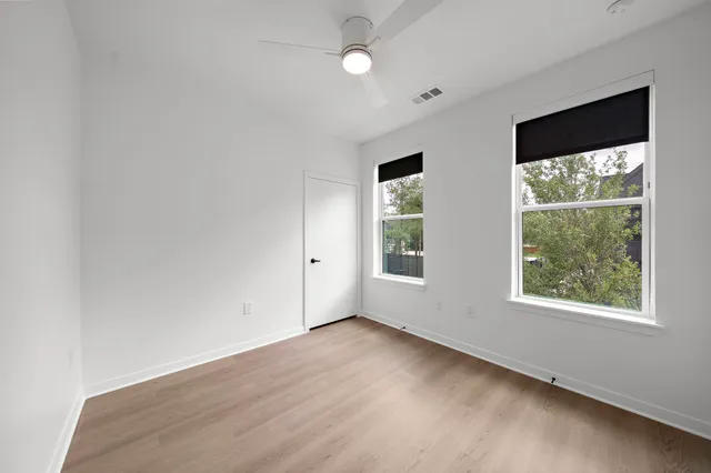 an empty room with wooden floor and windows