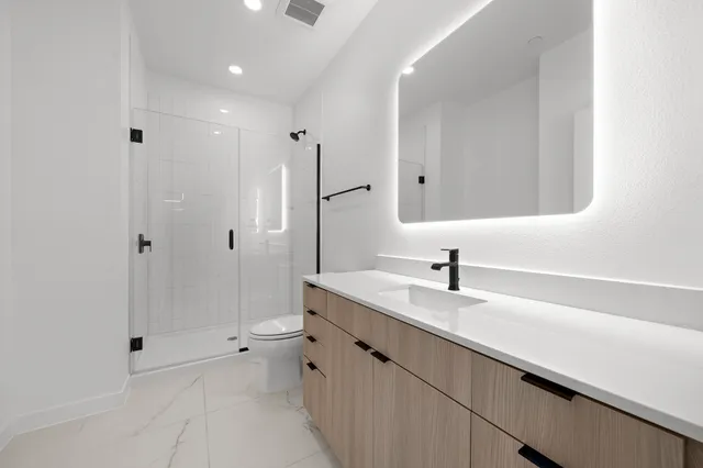 a bathroom with a granite countertop sink a toilet and shower