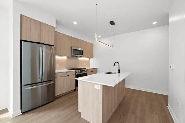 a kitchen with a sink stainless steel appliances and wooden floor