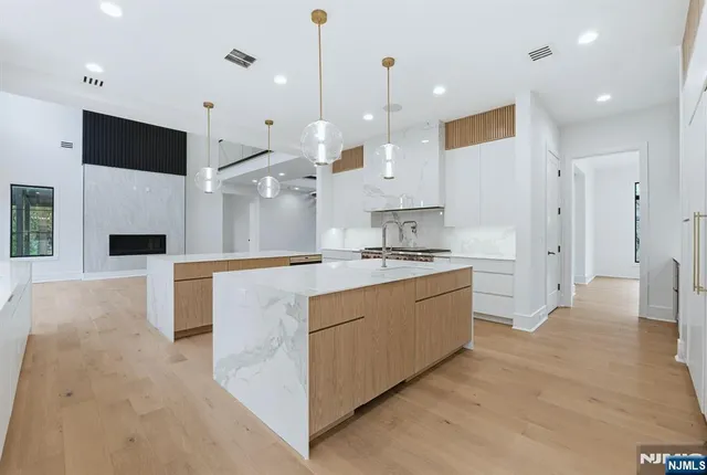 a large kitchen with stainless steel appliances kitchen island a large counter top a sink and a refrigerator