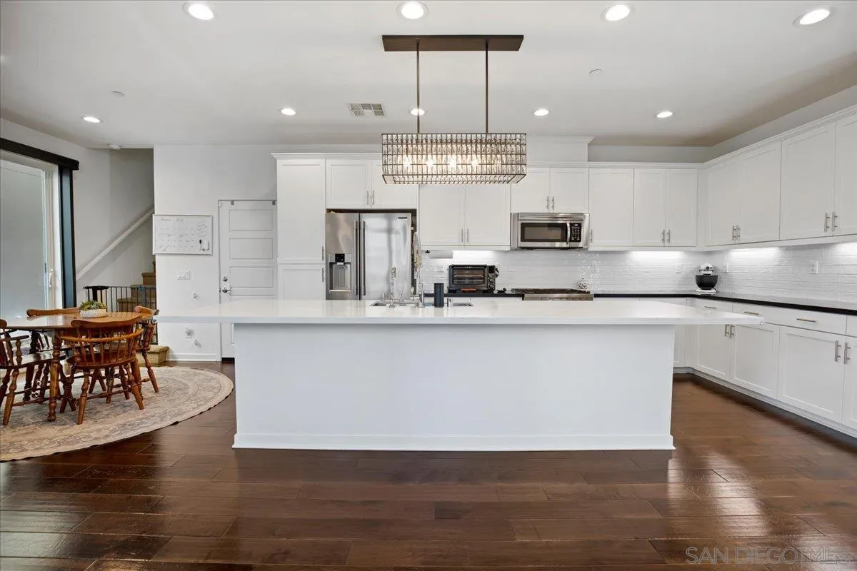 2123 Element Way Chula Vista, CA 91915 - Photo 8 of 42 a kitchen with stainless steel appliances granite countertop a stove a sink a refrigerator and a dining table with wooden floor