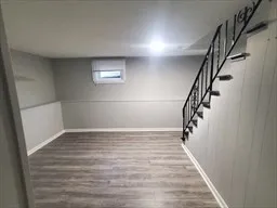 a view of an empty room with stairs and wooden floor