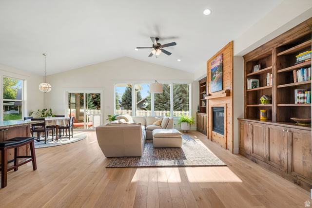 1238 Canyon View Road Midway, UT 84049 - Photo 3 of 33 Vaulted ceiling living area featuring light wood-finish flooring, a built-in fireplace with wood surround, extensive built-in wooden shelving, and large windows