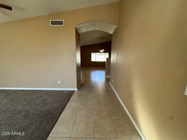 an empty room with a chandelier fan and windows