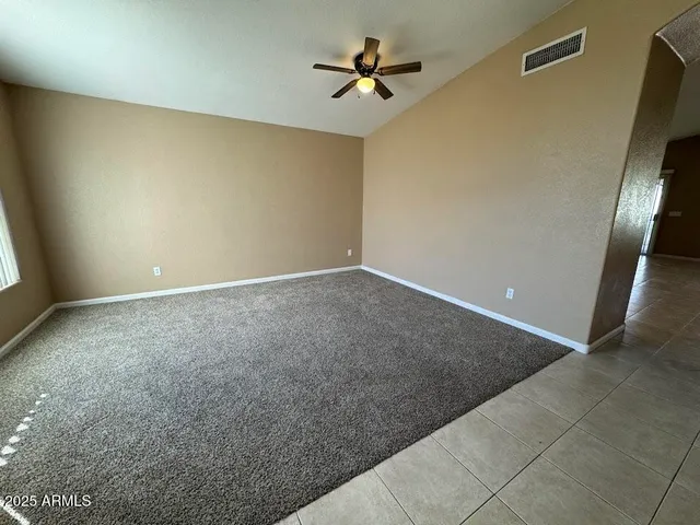 an empty room with a fan and windows