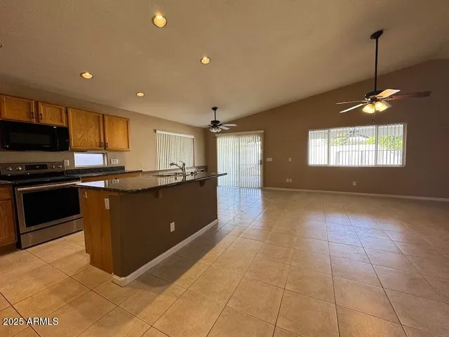 a view of a kitchen with kitchen island a counter top space a sink stainless steel appliances and cabinets