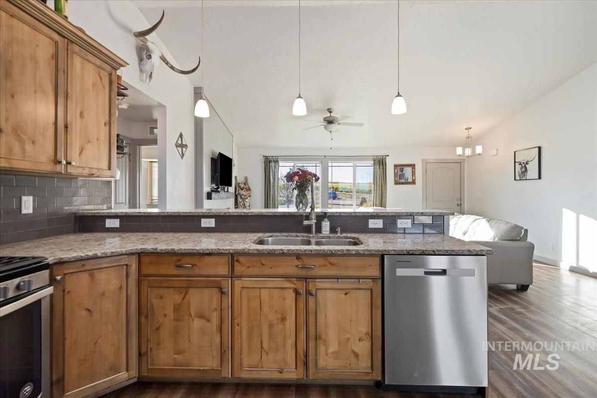 17571 Goodson Road Caldwell, ID 83607 - Photo 36 of 36 Kitchen with open floor plan, stainless steel appliances, brown cabinetry, a peninsula, and dark wood-style flooring