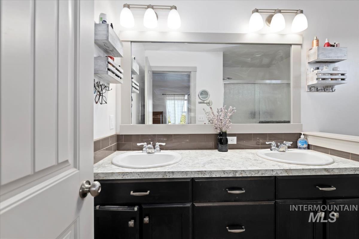 17571 Goodson Road Caldwell, ID 83607 - Photo 13 of 36 Bathroom with a stall shower, double vanity, and tasteful backsplash