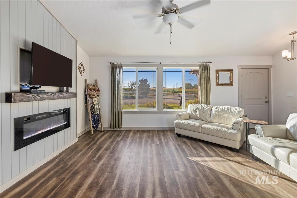 17571 Goodson Road Caldwell, ID 83607 - Photo 15 of 36 Living area featuring dark wood finished floors, a glass covered fireplace, and ceiling fan