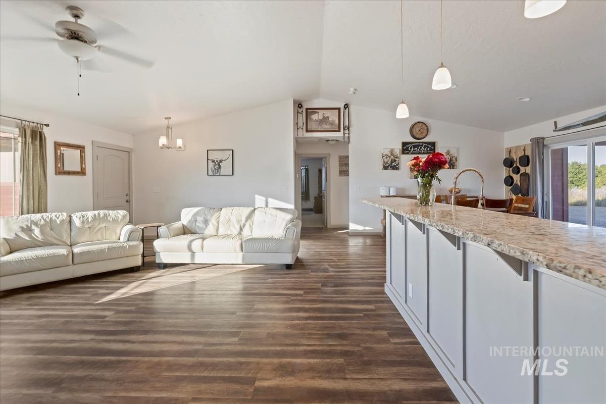17571 Goodson Road Caldwell, ID 83607 - Photo 20 of 36 Living room featuring plenty of natural light, lofted ceiling, dark wood-style flooring, ceiling fan, and a chandelier