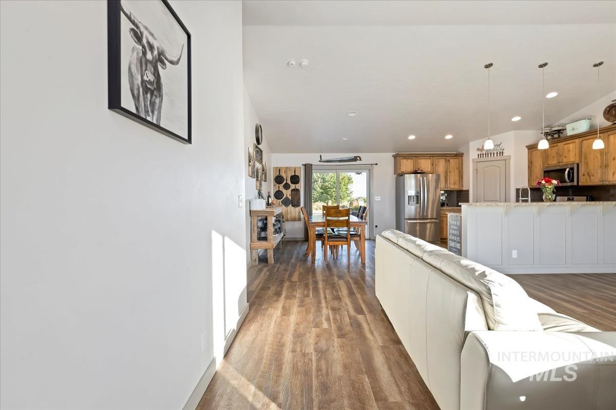 17571 Goodson Road Caldwell, ID 83607 - Photo 34 of 36 Kitchen featuring open floor plan, decorative light fixtures, stainless steel appliances, dark wood-style floors, and brown cabinetry