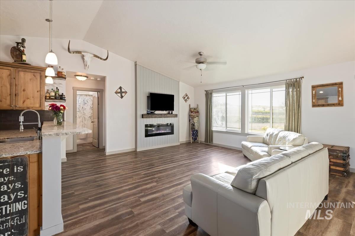 17571 Goodson Road Caldwell, ID 83607 - Photo 5 of 36 Living area featuring dark wood-style floors, lofted ceiling, a ceiling fan, and a large fireplace