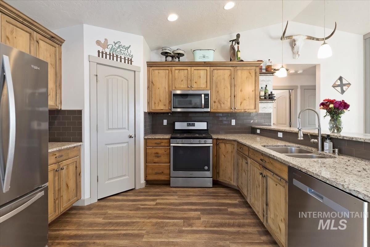 17571 Goodson Road Caldwell, ID 83607 - Photo 8 of 36 Kitchen with appliances with stainless steel finishes, light stone counters, vaulted ceiling, backsplash, and decorative light fixtures