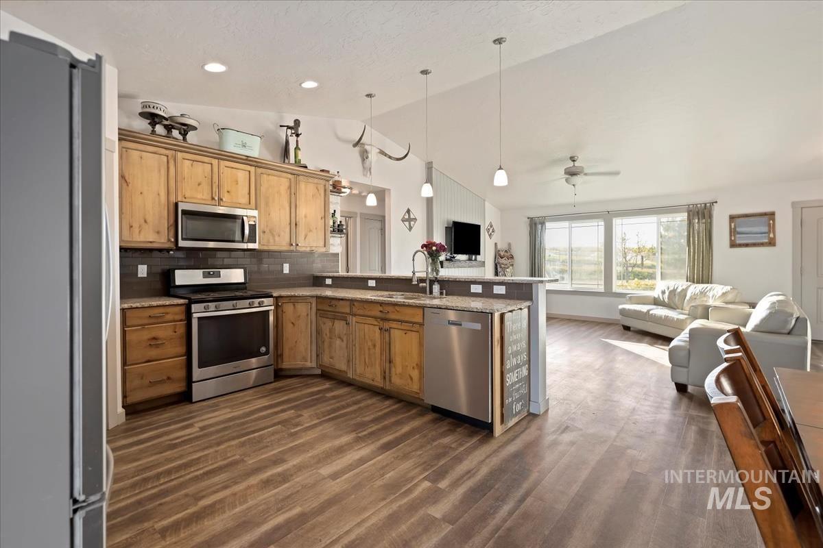 17571 Goodson Road Caldwell, ID 83607 - Photo 35 of 36 Kitchen with decorative light fixtures, stainless steel appliances, open floor plan, lofted ceiling, and tasteful backsplash