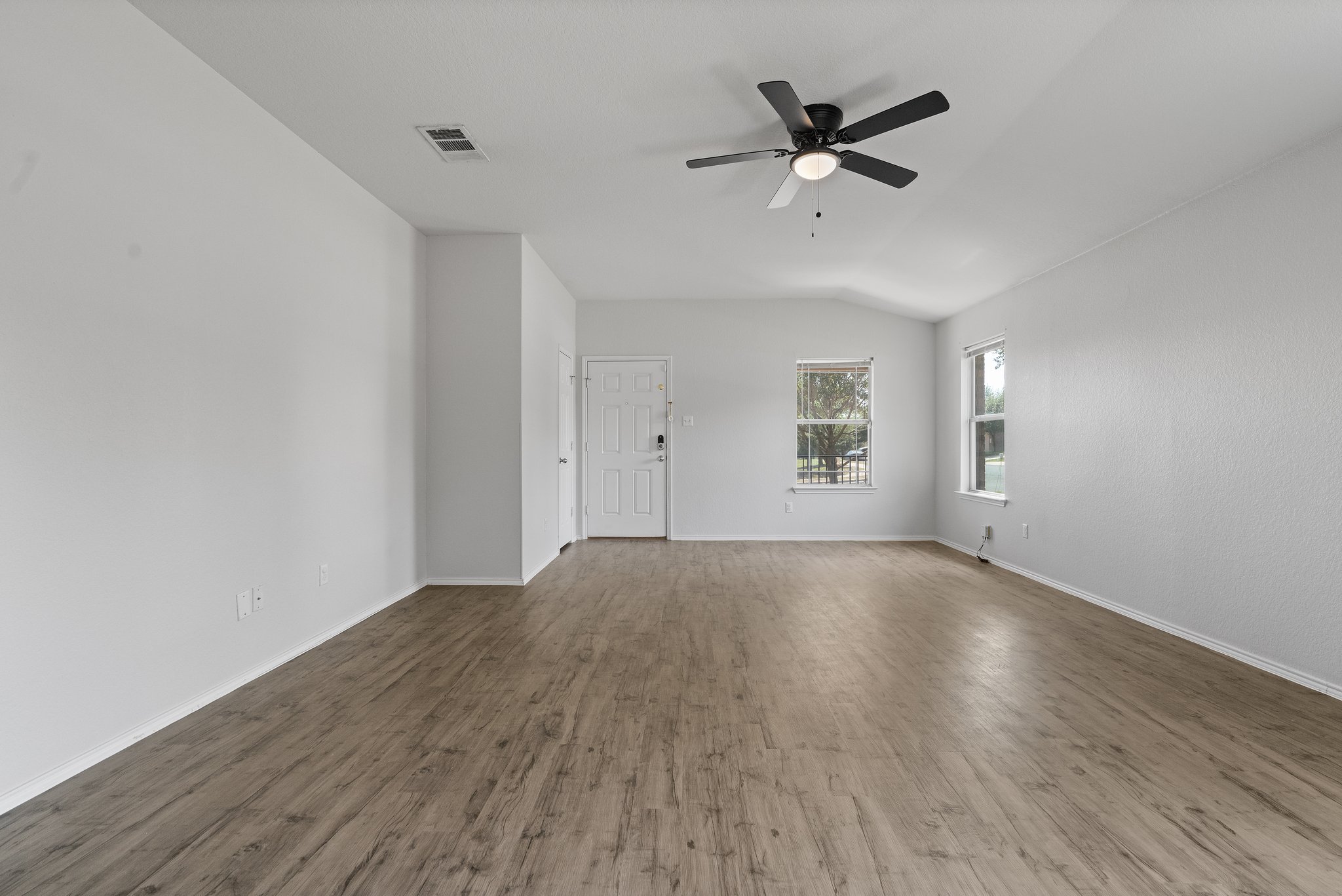 5800 Maciver Drive Austin, TX 78754 - Photo 12 of 27 Empty room featuring wood finished floors, vaulted ceiling, and a ceiling fan