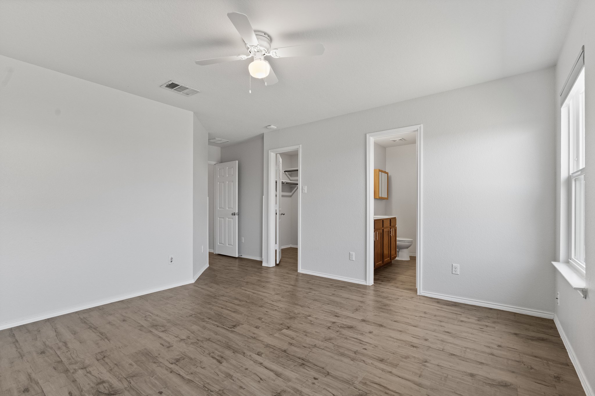 5800 Maciver Drive Austin, TX 78754 - Photo 15 of 27 Unfurnished bedroom with a spacious closet, ceiling fan, wood finished floors, and ensuite bathroom