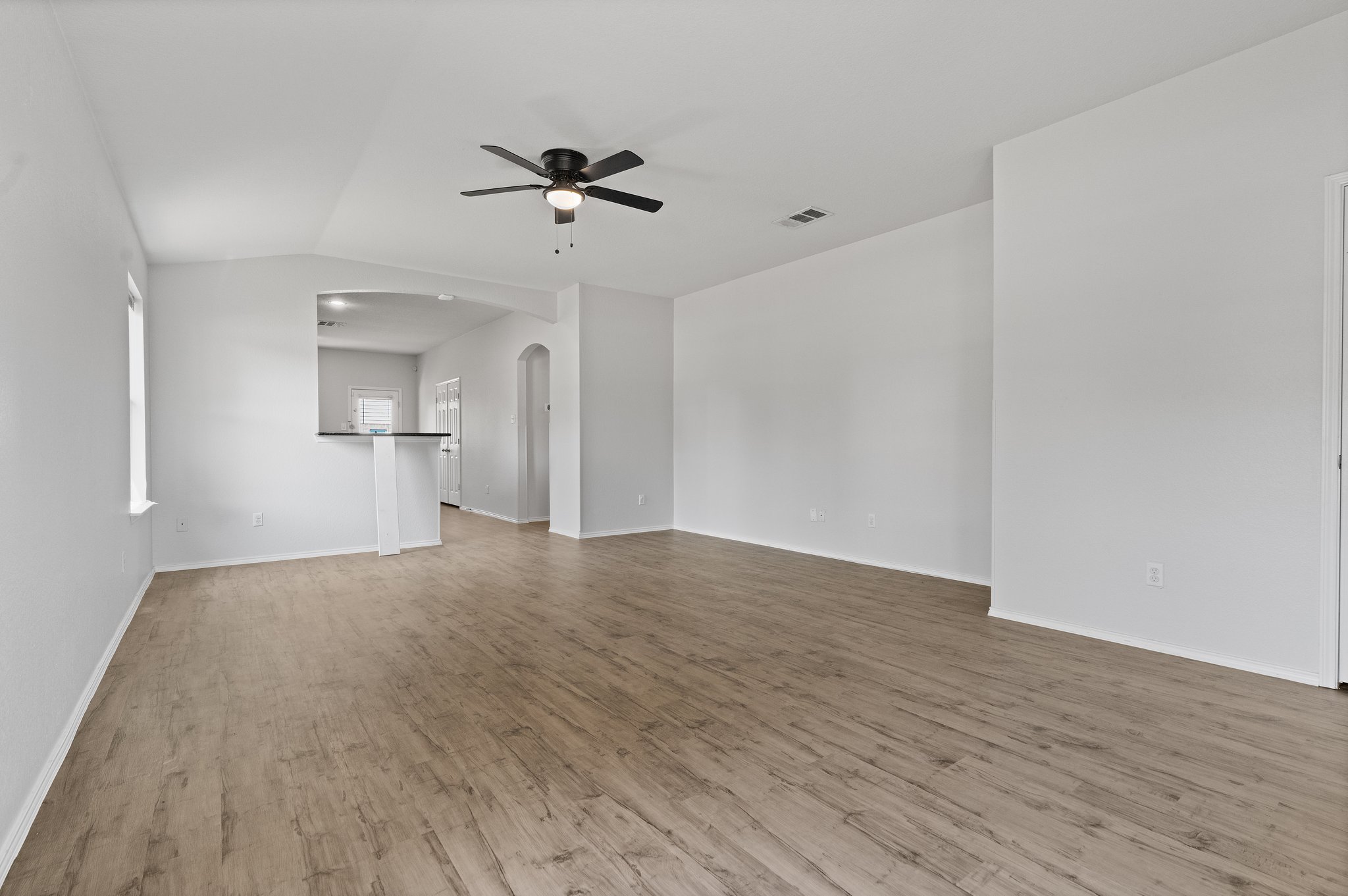 5800 Maciver Drive Austin, TX 78754 - Photo 4 of 27 Spare room featuring arched walkways, a ceiling fan, light wood-style flooring, and vaulted ceiling