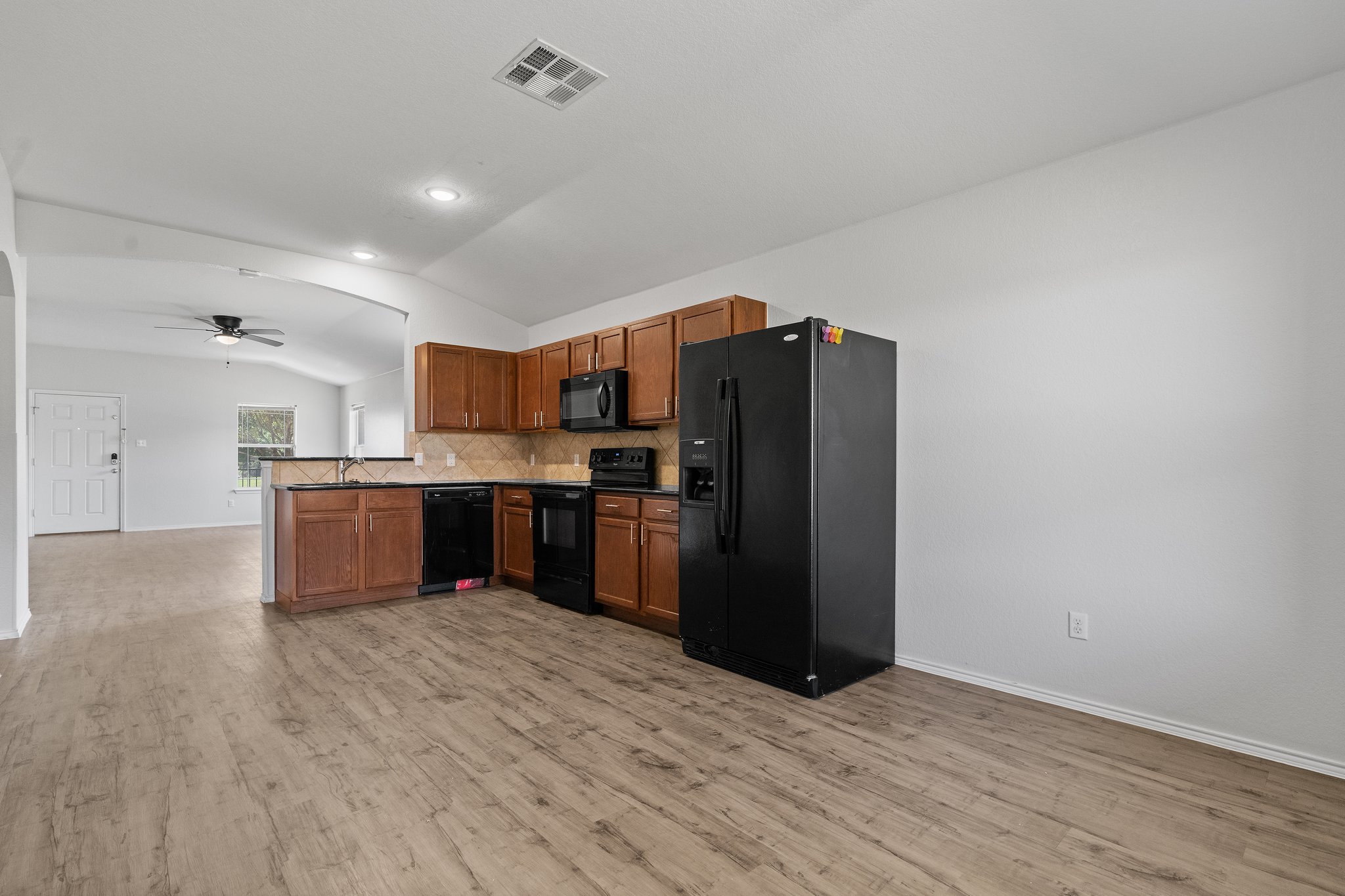 5800 Maciver Drive Austin, TX 78754 - Photo 27 of 27 Kitchen with black appliances, vaulted ceiling, brown cabinetry, ceiling fan, and open floor plan