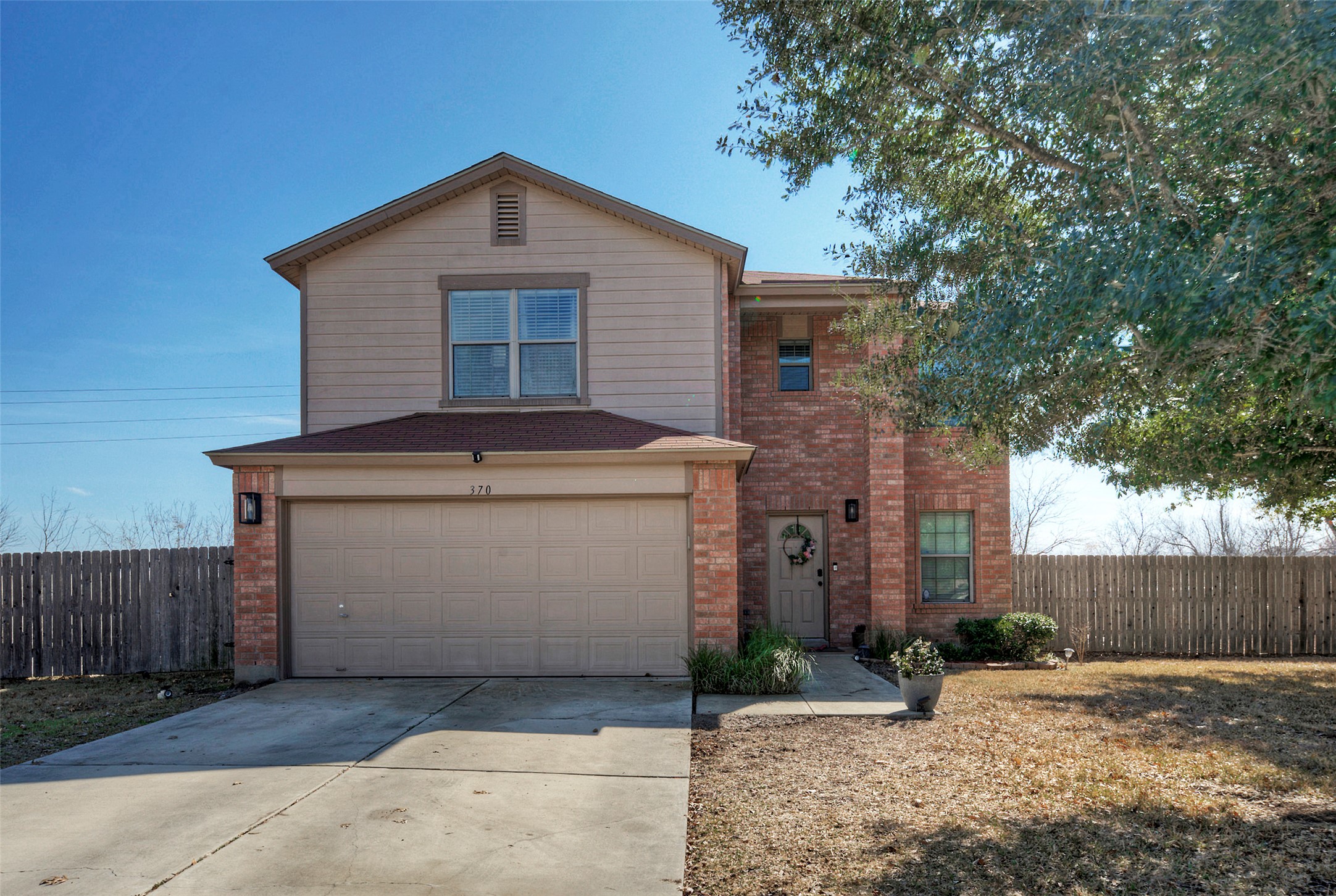 Traditional-style home featuring an attached garage, driveway, and brick siding