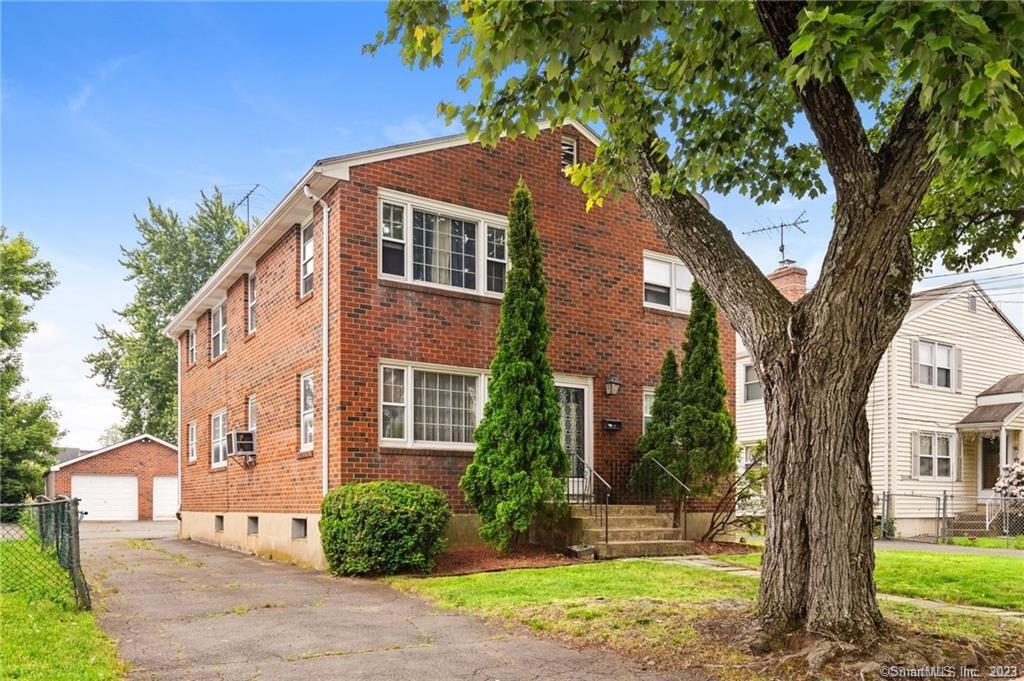 a front view of a house with a yard and an tree