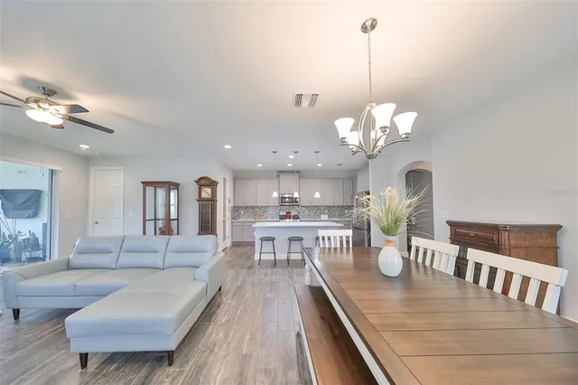 a kitchen with stainless steel appliances granite countertop a refrigerator a sink dishwasher a stove and white cabinets with wooden floor