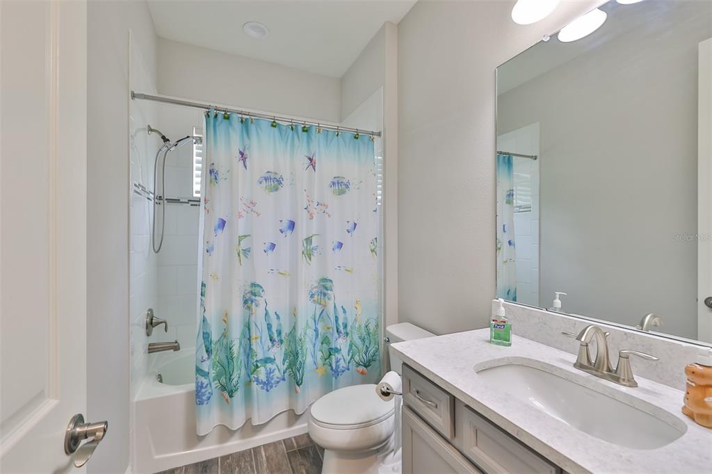 7411 Windport Lane Apollo Beach, FL 33572 - Photo 35 of 71 a bathroom with a granite countertop sink a toilet a mirror and shower curtain