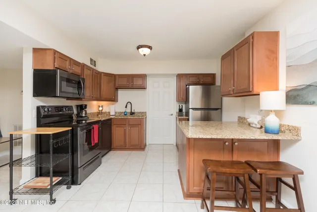 a kitchen with stainless steel appliances granite countertop a stove top oven a sink a dining table and chairs