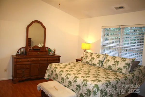 a bedroom with a bed and a dresser with wooden floor