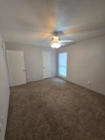 a view of an empty room with a chandelier fan