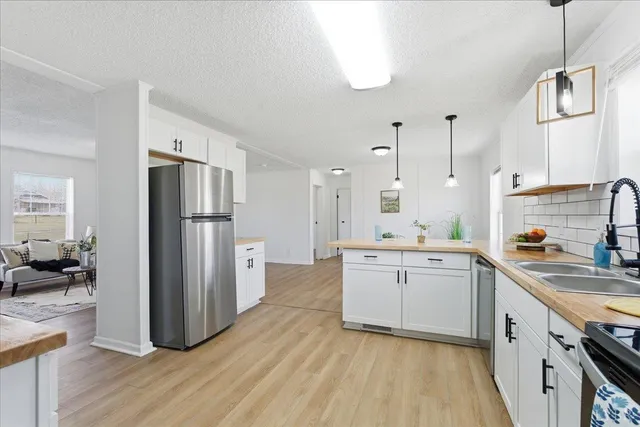 a kitchen with a refrigerator a sink dishwasher and a stove with wooden floor