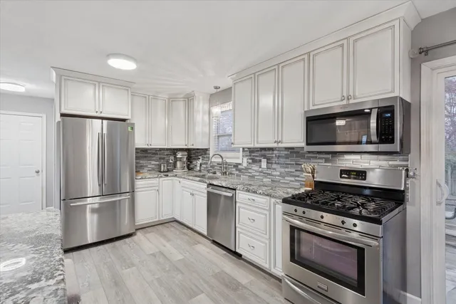 a kitchen with cabinets stainless steel appliances and wooden floor
